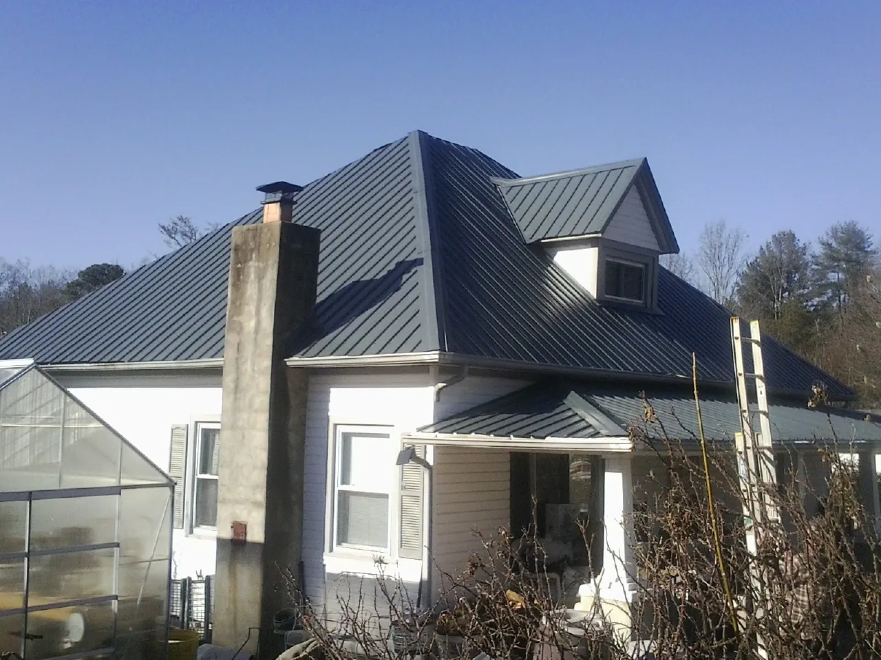 Dark blue standing seam metal roof on a white farmhouse with dormer — Slate & Tile Roof Repair by Roofing Brothers in Huson