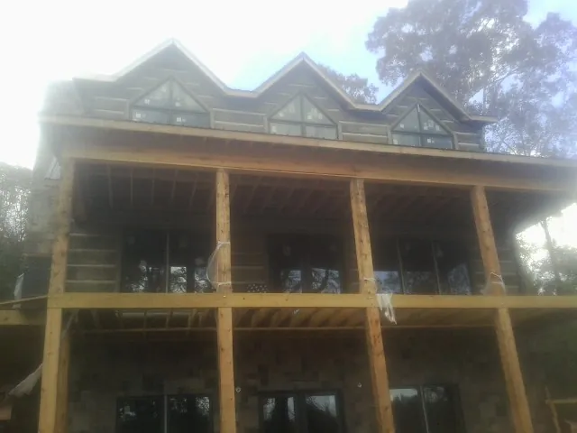 Dormers and porch framing on a large log home under construction — Roof Coating work by our crew in Huson