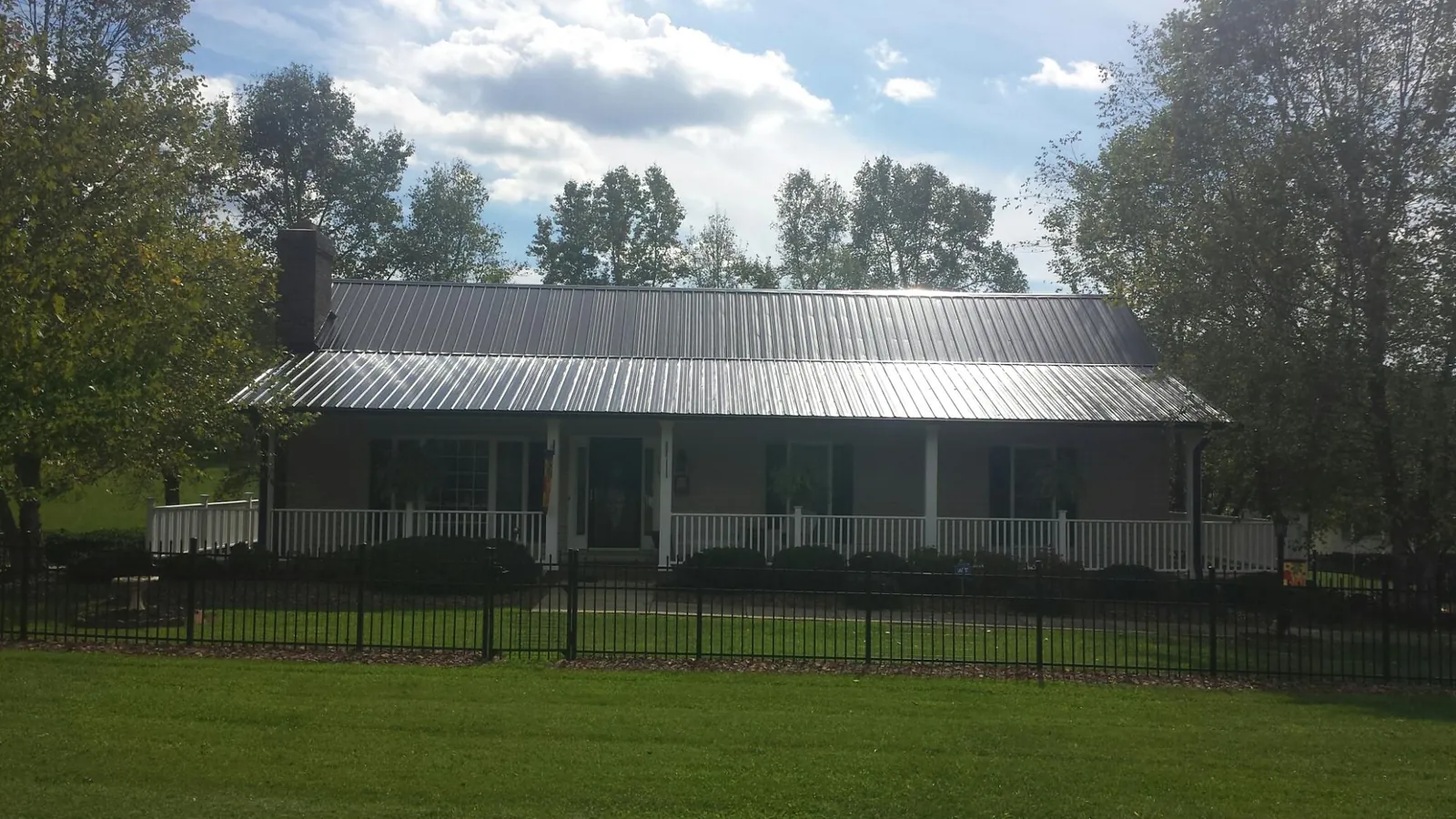 Gray metal roof on a brick ranch with a full width front porch — Gutter Guard Installation work by our crew in Huson