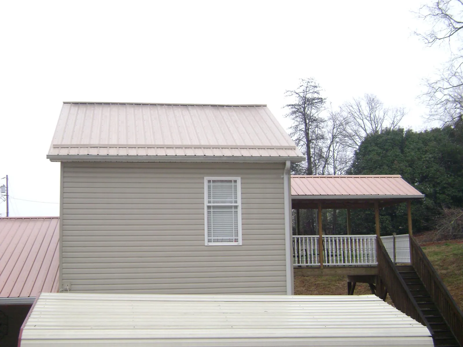 Tan metal roofs on a two story addition and attached porch, from a Roof Replacement job in Huson